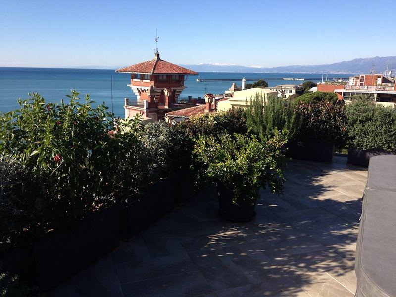 Terrazzo a Genova con roseto ornamentale, alloro e leccio in vaso, vista mare — realizzazione Peirano Vivai